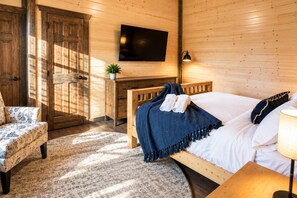 A room with a bed, a chair, a desk, a television, and a lamp. - Luxury Smoky Retreat | Pool, Theater & Hot Tub (Sevierville)