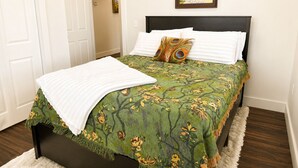 A bedroom with a bed, a pillow, a painting on the wall, and a door.
