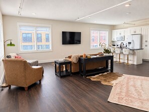 A modern living room with a sofa, a coffee table, and a TV mounted on the wall. - Brand New - The Moss-DeGraff - Downtown - Lawn (Joplin)