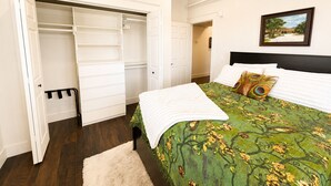 A bedroom with a bed, a closet, and a painting on the wall.