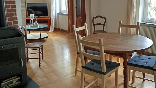 A dining area with a round wooden table, four chairs, a television, and a fireplace. - Vacation Home in a Rural Setting (Heidwiller)