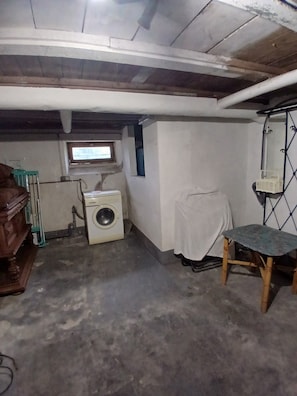 A laundry room with a washing machine, a wooden chair, and a small table.