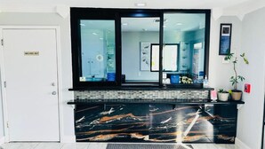 Zona de recepción con mostrador de mármol, una puerta con la leyenda 'Solo personal' y una planta en maceta.
