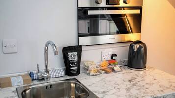 A modern kitchen with a stainless steel sink, a kettle, a coffee maker, and a bag of coffee beans.