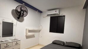 Un dormitorio con cama, cómoda, espejo, ventilador y aire acondicionado.
