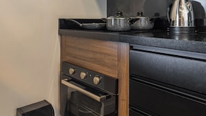 Una cocina compacta con horno integrado, estufa y extractor de humos.