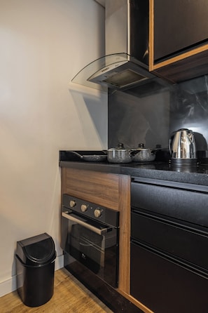 Una cocina compacta con horno integrado, estufa y extractor de humos.