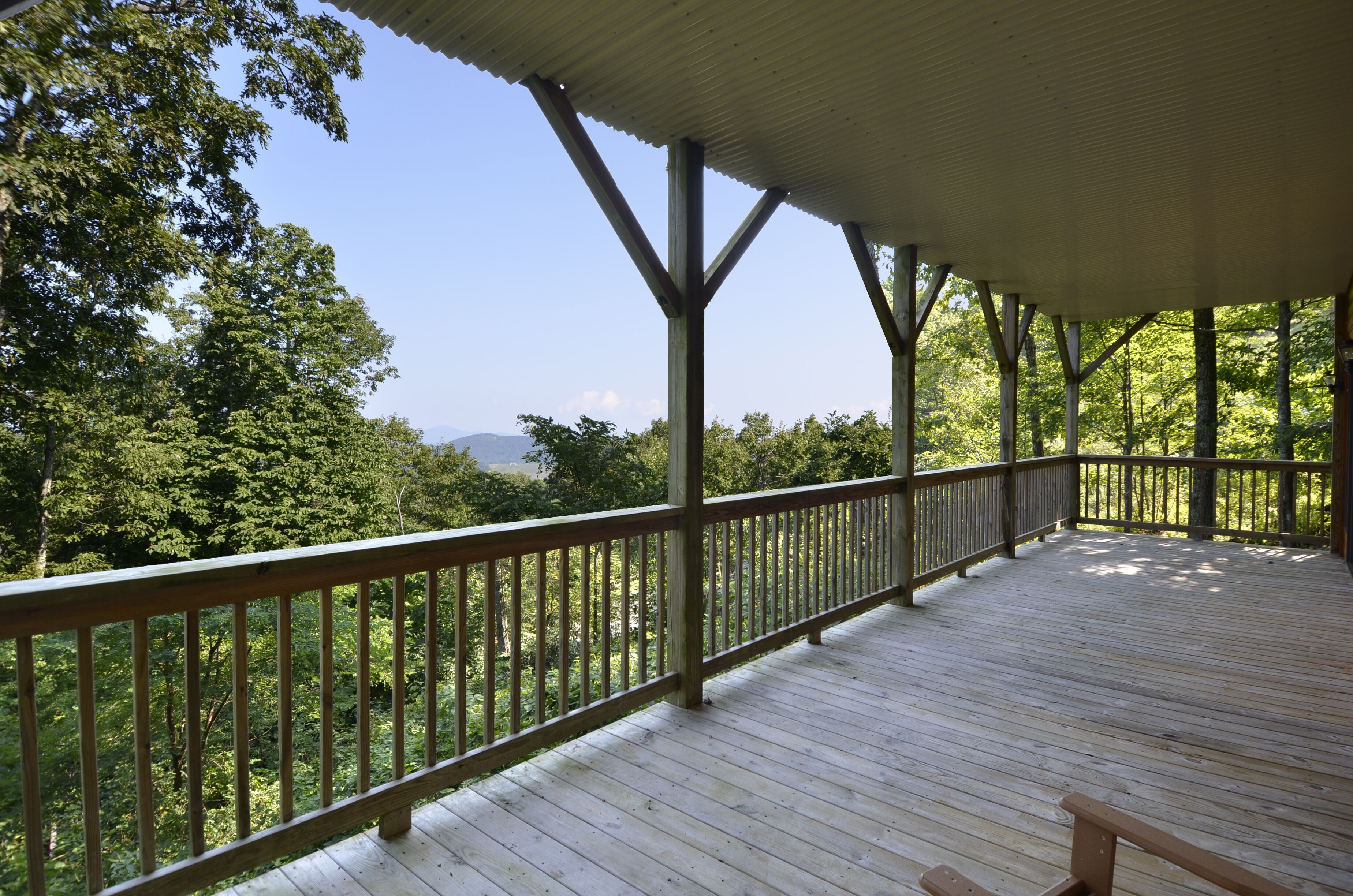 A wooden deck with a metal railing overlooking a forested area.