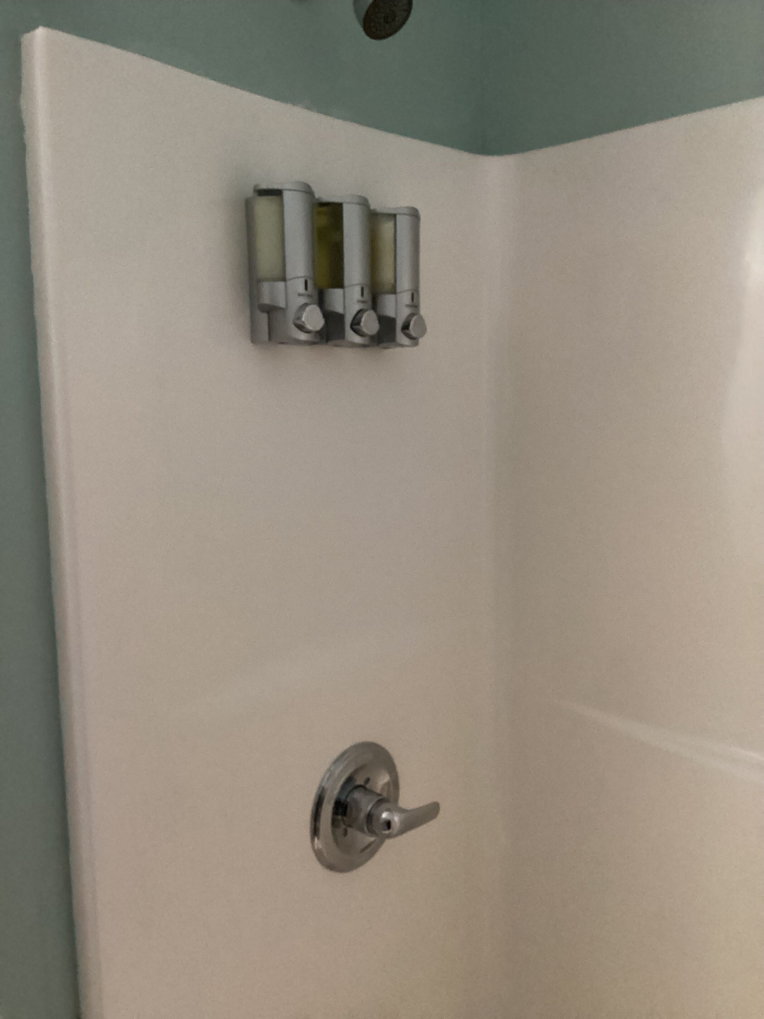 A white shower enclosure with a control panel and a single lever.