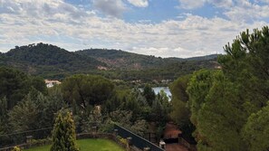 A view of a mountainous landscape with a lake, surrounded by dense greenery and trees.