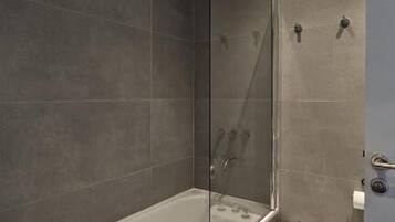 Een moderne badkamer met een douchecabine, een bad, een wastafel op een zuil en een toilet met douchefunctie.