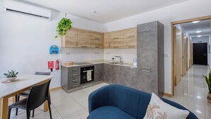 A modern kitchen with wooden cabinets, a built-in oven, and a grey refrigerator. - Belmonte Heights Flat 2BDR (Sliema)