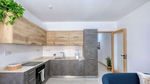 A modern kitchen with grey cabinets, a black oven, and a stainless steel sink. - Belmonte Heights Flat 2BDR (Sliema)