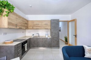 Eine moderne Küche mit grauen Schränken, einem schwarzen Backofen und einer Spüle aus Edelstahl.