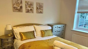 A bedroom with a bed, bedside table, and a window with blinds.