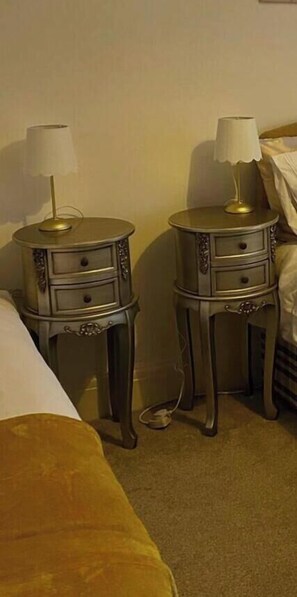 A hotel room with two bedside tables, each with a lamp, a bed, and a carpeted floor.