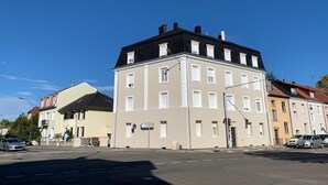 En byggnad med flera våningar, ett platt tak, stora fönster och en gata framför.