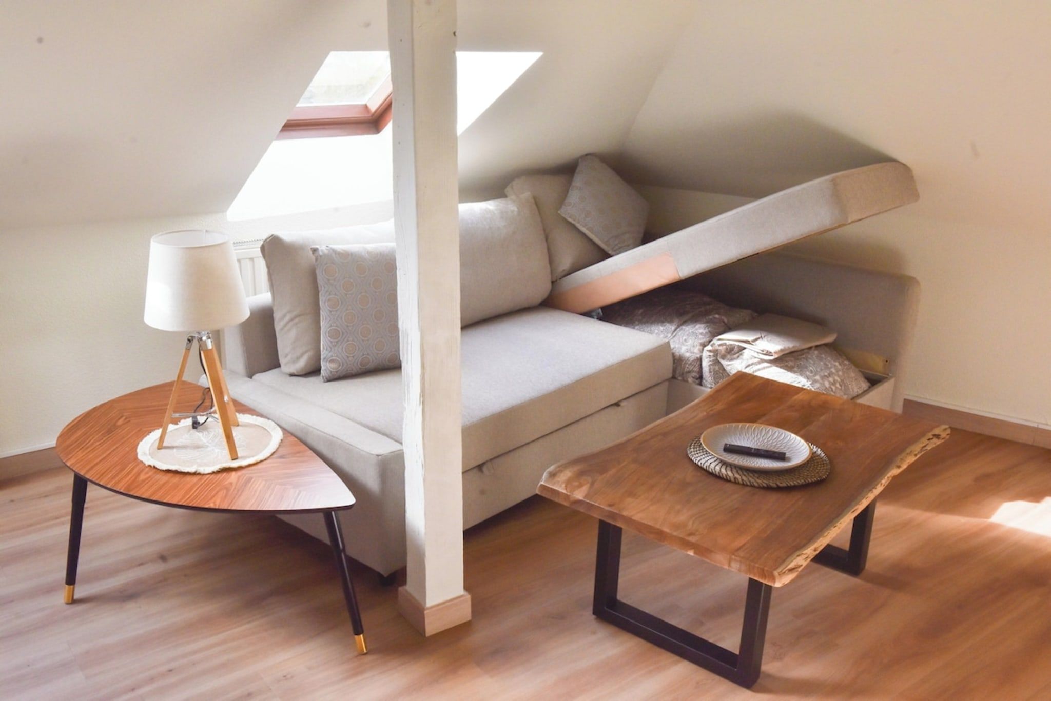 Ein Zimmer im Loft-Stil mit einer Couch, einem kleinen Tisch und einer Lampe.