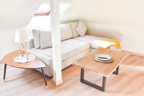 A modern living room with a sofa, a coffee table, and a lamp. - Apogee Mulhousienne - Cozy attic apartment, AC, Wi-Fi (Mulhouse)