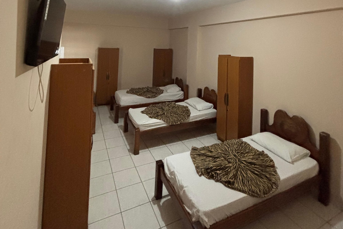 Habitación de hotel con dos camas individuales, televisor y armario.