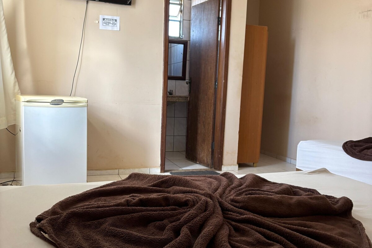 Habitación de hotel con cama, televisión montada en la pared, un escritorio pequeño y una puerta que da a un baño.