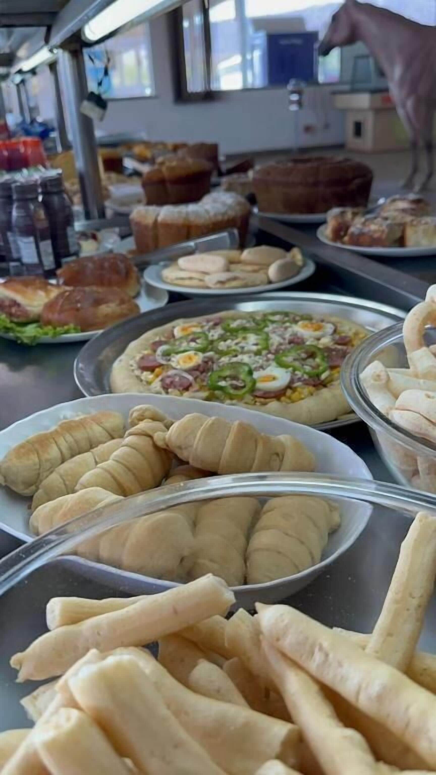 A variety of baked goods including pastries, bread, and a pizza on display.
