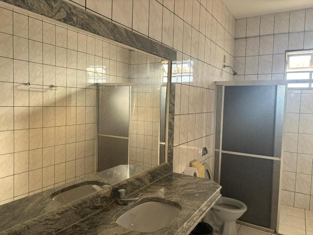 Baño con lavamanos doble, espejo y cabina de ducha.