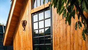 Una cabaña de madera con puerta de vidrio, un letrero sobre la puerta y una escalera de madera que conduce a la entrada.
