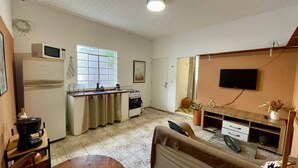 Um espaço compacto com cozinha americana, televisão e sofá.