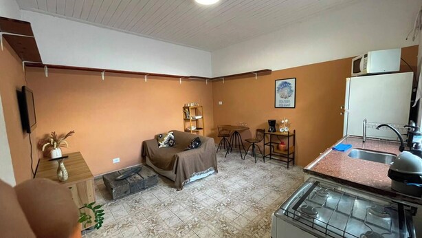 Um espaço compacto com cozinha compacta, área de jantar e sala de estar com sofá e cadeiras.