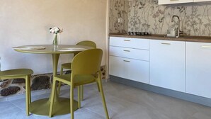 Een keuken met witte kastjes, een ronde tafel met stoelen en een hanglamp.