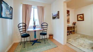 A room with a table and two chairs, a window with curtains, a bookshelf, and a framed picture on the wall. - Serene 10-Acre Nevada City Retreat w Hot Tub! (Nevada City)