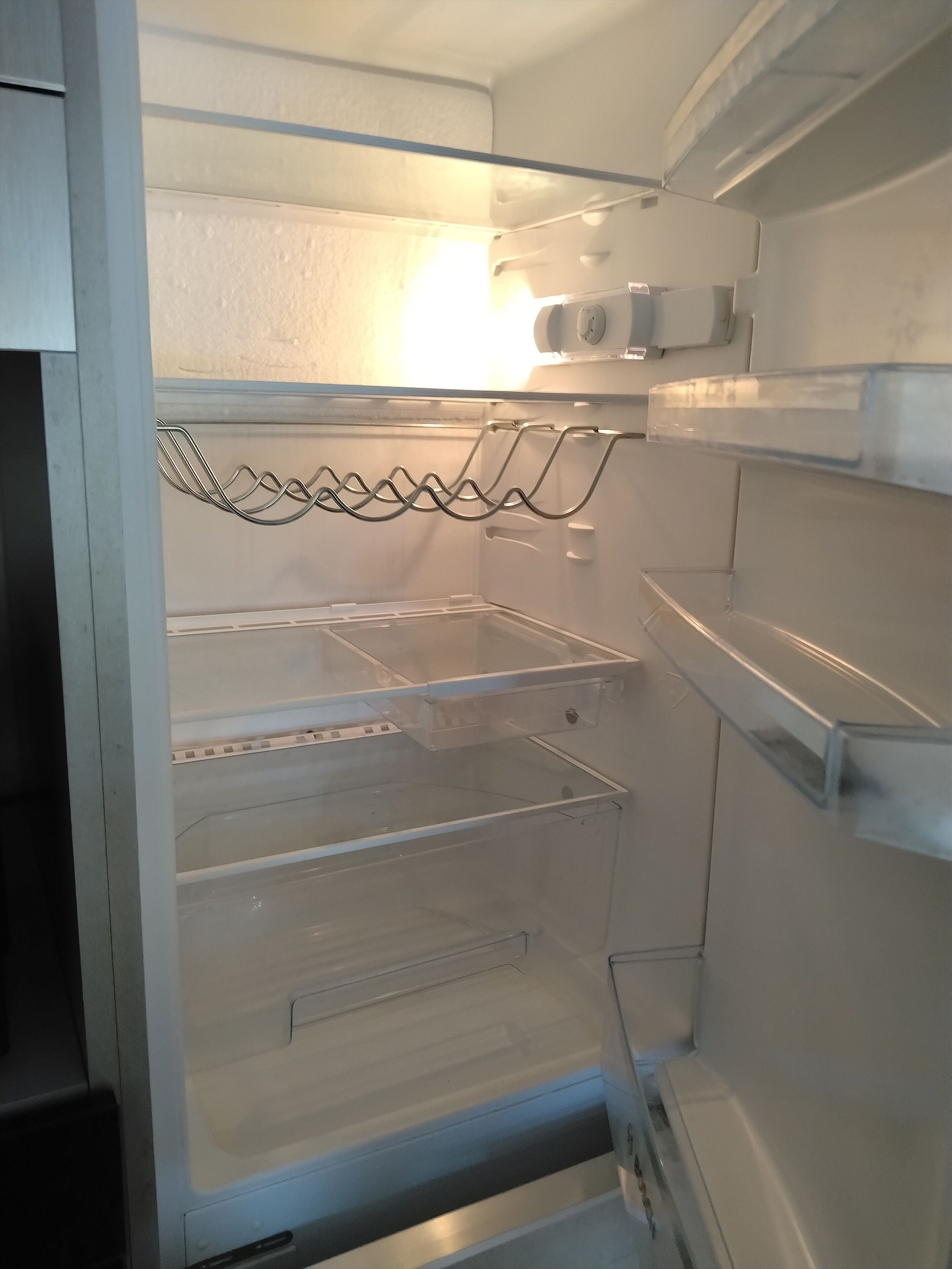An empty refrigerator with multiple shelves and a wire rack.