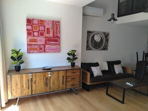 A modern living room with a wooden cabinet, a black sofa, and two potted plants. - L'Instant Sud in Châteauneuf-de-Grasse (Châteauneuf-Grasse)
