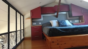 A bedroom with a sloped ceiling, a bed with a dark blue blanket, red and grey cabinets, and a wooden headboard. - L'Instant Sud in Châteauneuf-de-Grasse (Châteauneuf-Grasse)