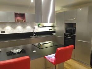 A modern kitchen with a central island, stainless steel appliances, and red chairs. - L'Instant Sud in Châteauneuf-de-Grasse (Châteauneuf-Grasse)