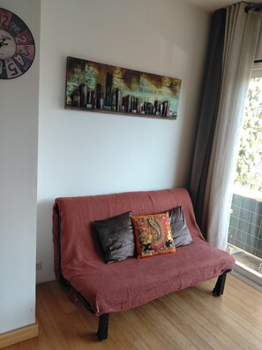 A red sofa with two cushions, a cityscape painting on the wall, and a clock. - L'Instant Sud in Châteauneuf-de-Grasse (Châteauneuf-Grasse)