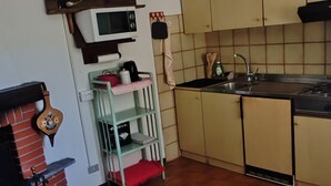 A kitchen with a microwave, stove, and hanging light fixture.