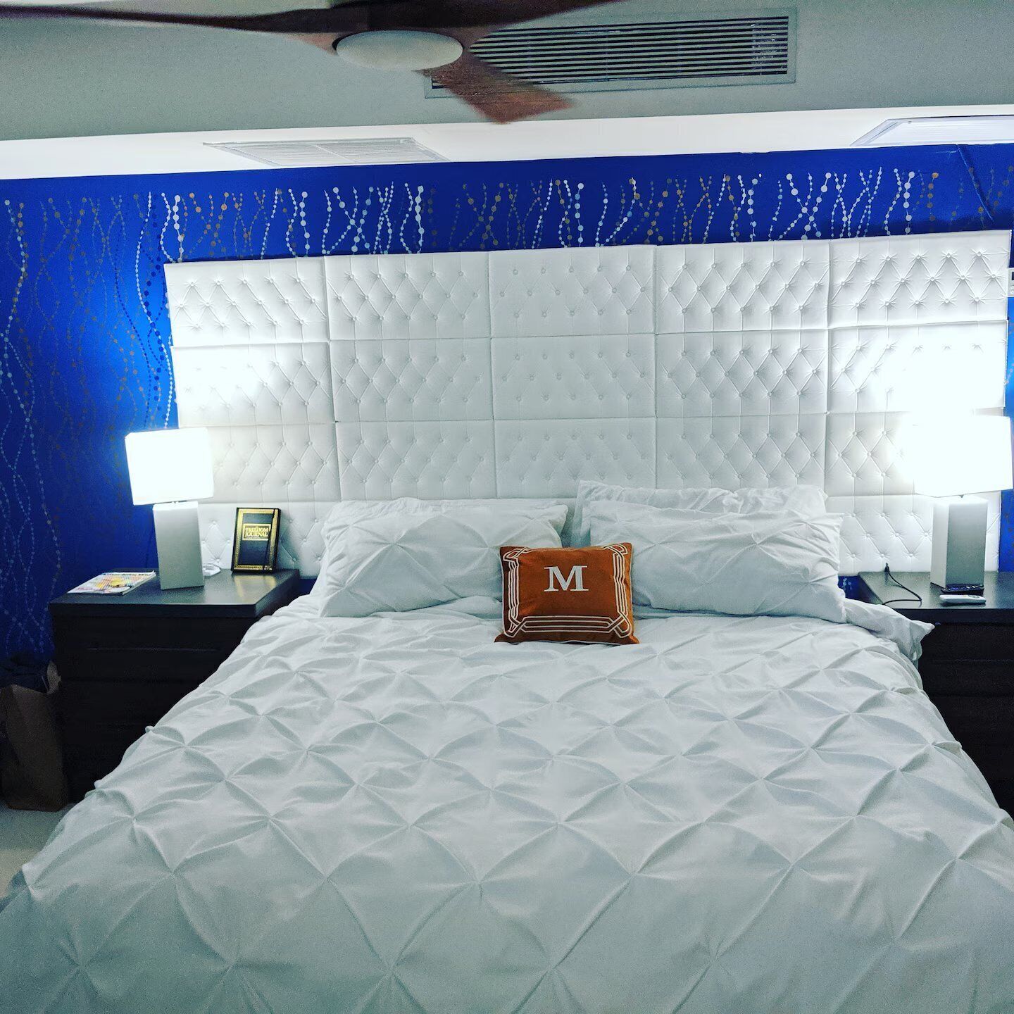 Ein Hotelzimmer mit einem großen Bett, einem Kopfteil, zwei Nachttischen und einem Beistelltisch.