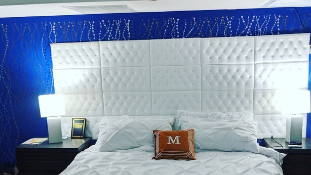 Ein Hotelzimmer mit einem großen Bett, einem Kopfteil, zwei Nachttischen und einem Beistelltisch.