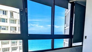 Ein Zimmer mit großem Fenster mit Blick auf ein Gewässer und ein Gebäude gegenüber.