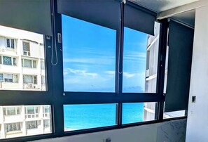 Ein Zimmer mit großem Fenster mit Blick auf ein Gewässer und ein Gebäude gegenüber.