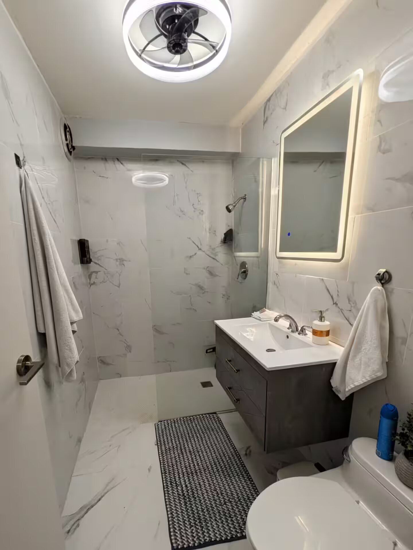 A modern bathroom with a shower, toilet, and sink.