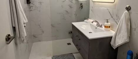 A modern bathroom with a shower, toilet, and sink.