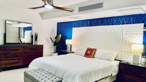 A modern bedroom with a large bed, a ceiling fan, a nightstand with a lamp, and a dresser. - ★Luxury Beachfront Oasis ~ Ocean Views ~ ♛King Bed (San Juan)