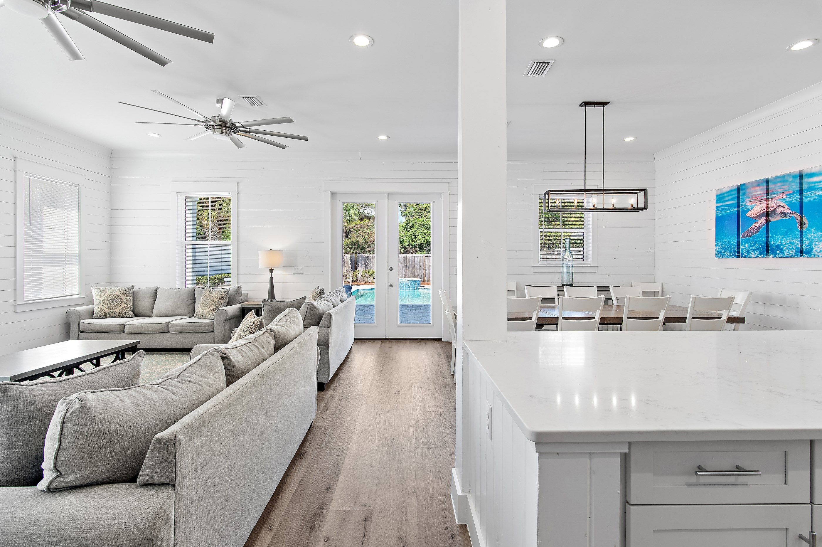 A modern kitchen with a large island, white cabinetry, and a ceiling fan.