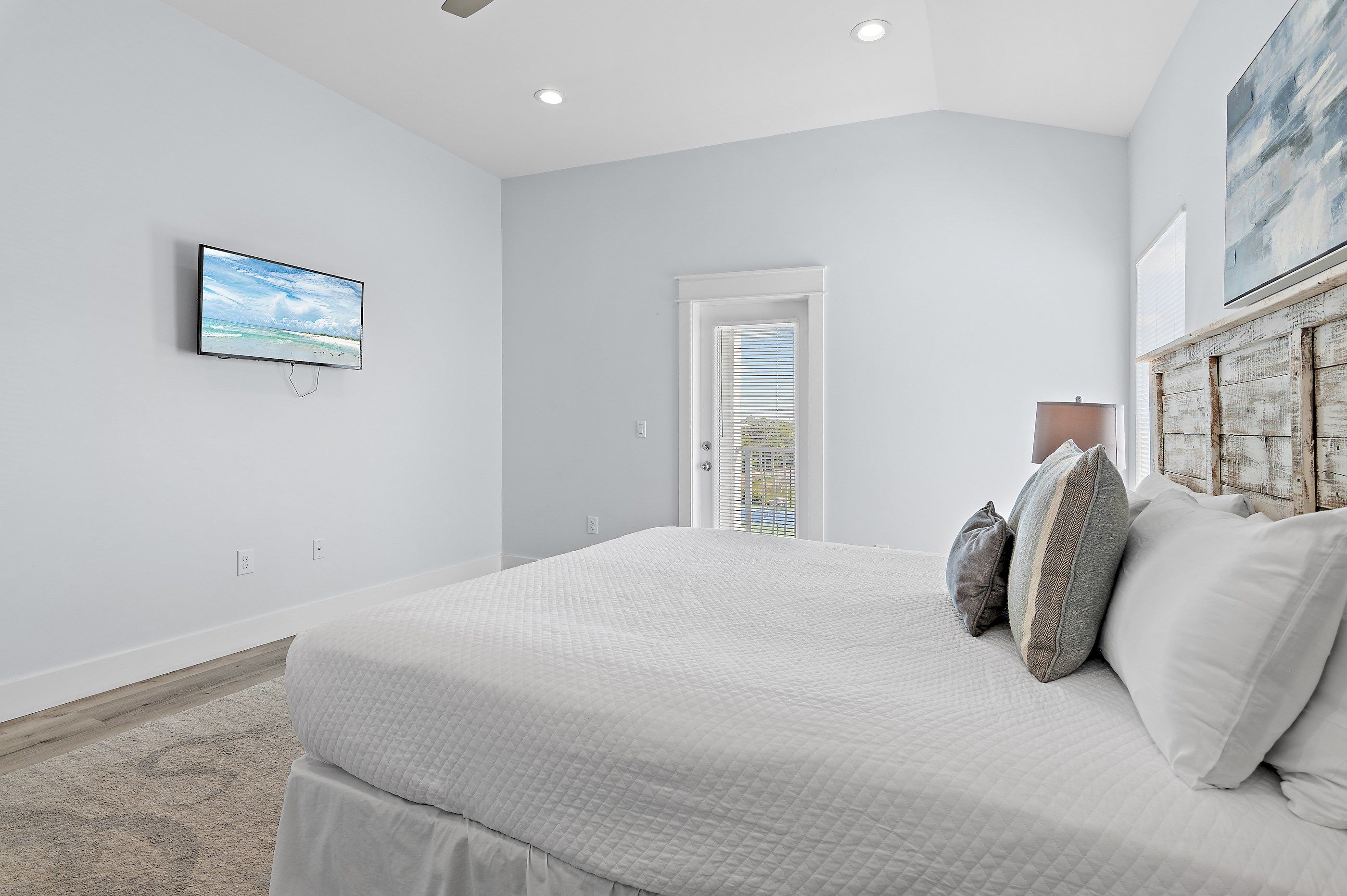 A bedroom with a bed, a television, a door, and a window.