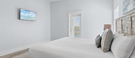A bedroom with a bed, a television, a door, and a window.