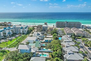 Un resort costero con varias construcciones, piscina y una playa al fondo.