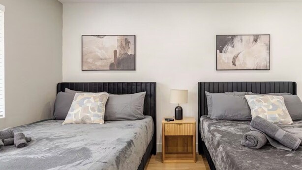 A double room with two beds, a nightstand with a lamp, and abstract wall art. - 3bed Near Beach, Wynwood Design District, Brickell (Miami)
